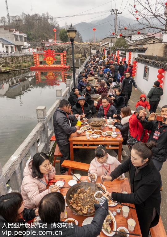 100张餐桌沿着南流河两岸，一字排开。大家围坐在一起，品美食、话家常，年味十足。